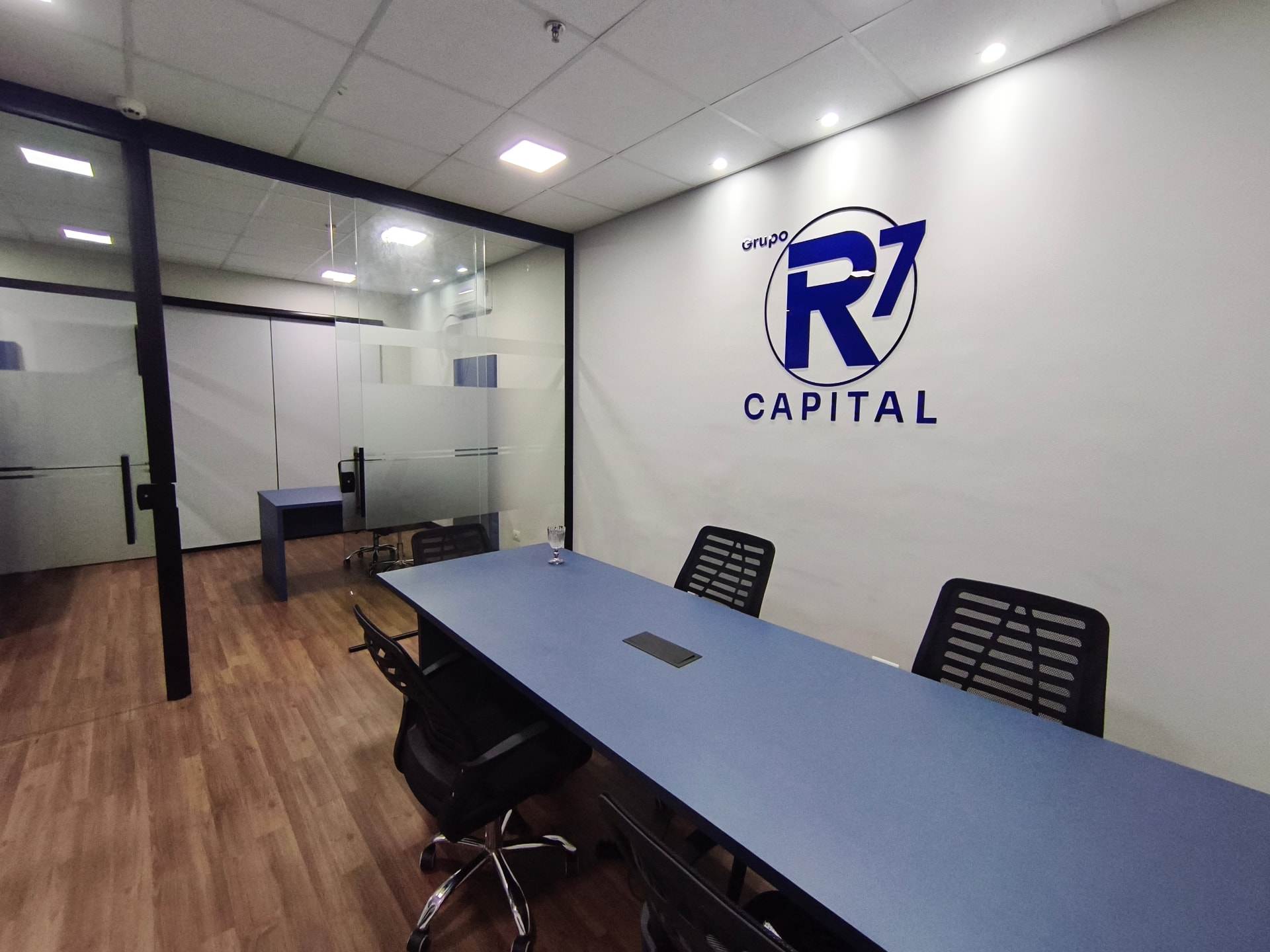 Sala de reunião da R7 Capital com o logotipo na parede